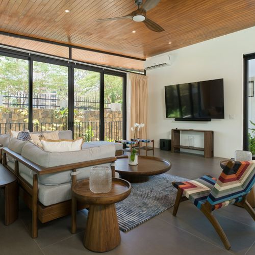 Air-conditioned indoor living room at Casa Oso luxury villa with glass walls opening to tropical garden views in Tamarindo, Costa Rica.