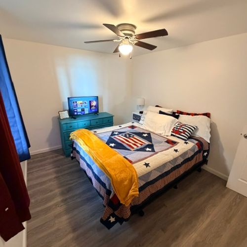 BEDROOM #1:  Features a queen-size bed, closet, dresser, television, nightstand, and a ceiling fan.