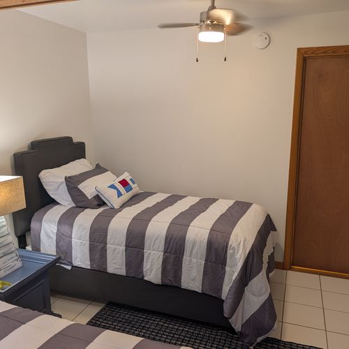 BEDROOM #4 (SECOND FLOOR):  Features 2 twin size beds, a dresser, mirror, nightstand, lamp, ceiling fan, and a clothes rack.