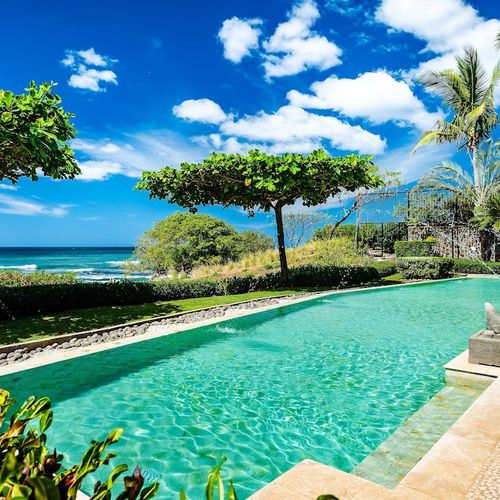 Beachfront pool with tropical garden and direct beach access gate at luxury Playa Langosta condo, Tamarindo, Costa Rica. Ocean views, pool lounge area, sun loungers, and steps from surf, restaurants, shops, and premium vacation rentals.