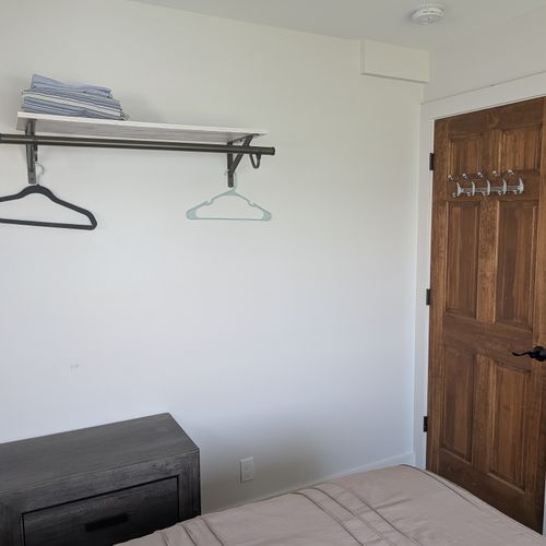 BEDROOM #4 (FIRST FLOOR):  Features a queen-size bed, private A/C unit, ceiling fan, television, dresser, mirror, nightstand, reading lamps, a clothes rack, and great views of Crystal Lake!