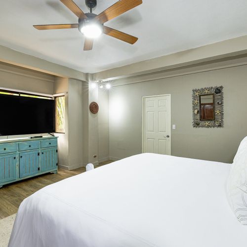 Casita king bedroom — turquoise distressed console, smart TV, starfish mirror.