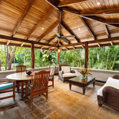 Screened lanai with vaulted exposed-beam ceiling, white wicker daybed and dining set at Casa Blue Lagoon beachfront villa, Tamarindo.