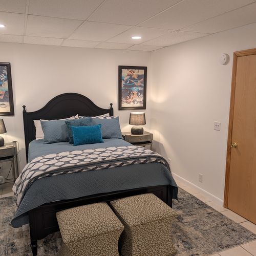 BEDROOM #1 (FIRST FLOOR):  Features a queen-size bed, nightstands, lamps, chair, dresser, and closet.
