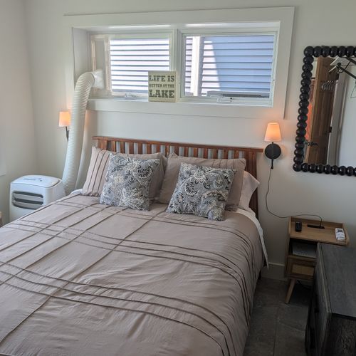 BEDROOM #4 (FIRST FLOOR):  Features a queen-size bed, private A/C unit, ceiling fan, television, dresser, mirror, nightstand, reading lamps, a clothes rack, and great views of Crystal Lake!