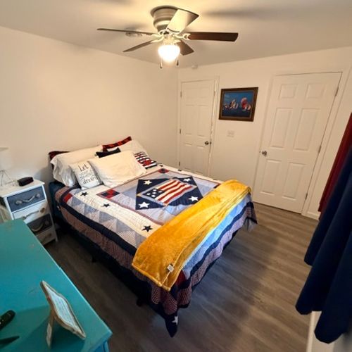 BEDROOM #1:  Features a queen-size bed, closet, dresser, television, nightstand, and a ceiling fan.