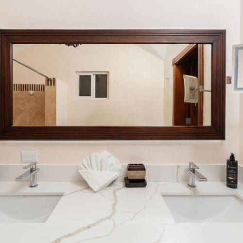 Elegant master bathroom with dual sinks, coastal decor, and stylish finishes at Playa Langosta condo in Tamarindo, Costa Rica. Accessed through walk-in closet, bright natural light, serene atmosphere, perfect for romantic getaways.