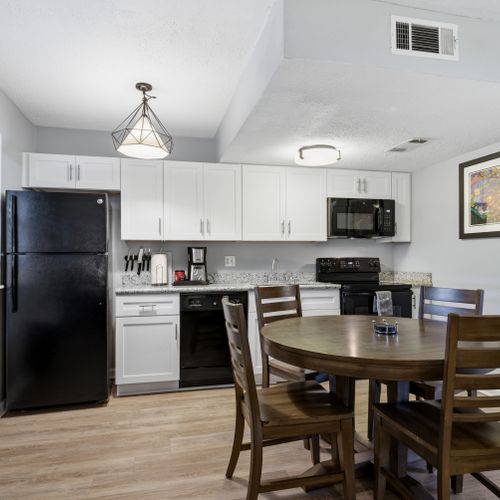 Clean, well-equipped kitchen w/ black appliances & white cabinetry