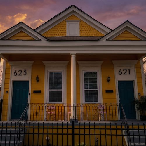 Classic New Orleans double shotgun façade w/ vibrant yellow & teal details.