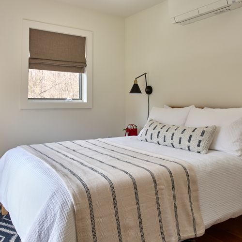 Across from the primary bedroom in the main house sits the first guest bedroom, looking out onto the pool and private meadow.