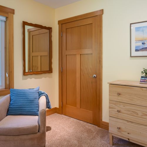 A cozy reading chair, dresser, and large window create a comfortable space to relax, unpack, and feel at home during your stay.
