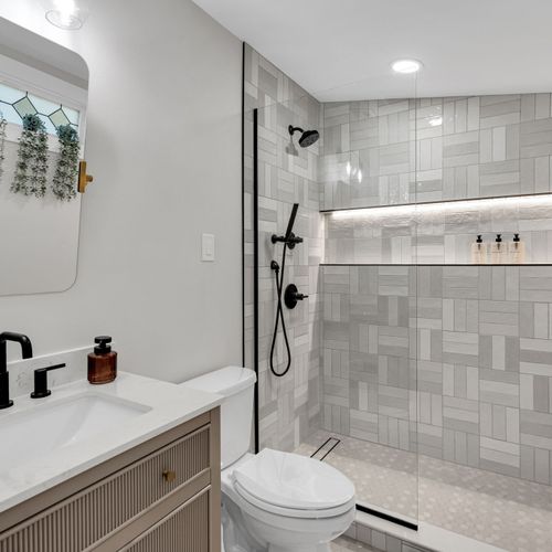 Refresh under the rainfall shower in this sleek bathroom w/ modern black fixtures & stylish tile