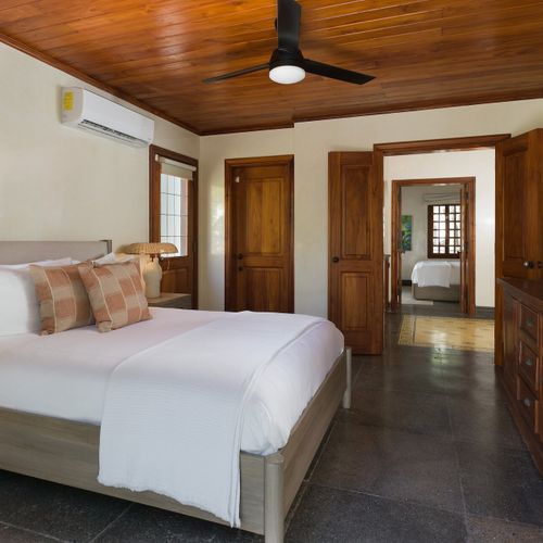 King bedroom with hardwood plank ceiling and connecting suite doors at Casa Libelula luxury beachfront estate, Tamarindo, Costa Rica.