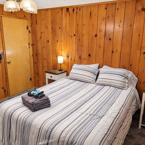 BEDROOM #1:   Features a queen-size bed, nightstands, lamp, dresser, closet, and chair.