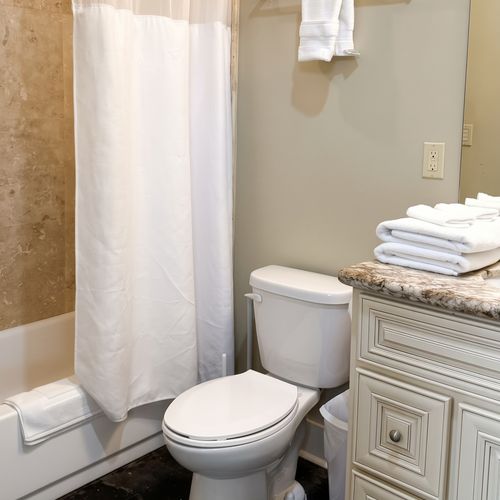 Clean bathroom with shower area and neatly arranged fresh towels