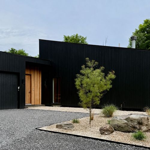 Arrive to a striking black-wood facade, a warm wood entry, and sculptural stone gardens.