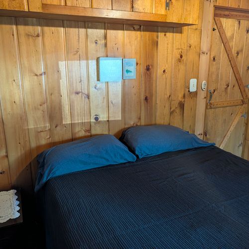 BEDROOM #1:  Features a queen-size bed, nightstand, clothes rack, and luggage stand.