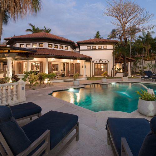 The estate at twilight - newly renovated Mediterranean architecture, terracotta tile roof, lit pool, steps from Langosta sand.