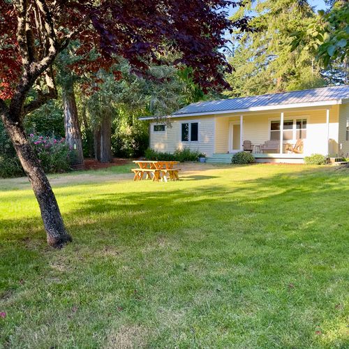 Unwind in the expansive yard with mature trees, open green space, and a picnic table for outdoor meals.