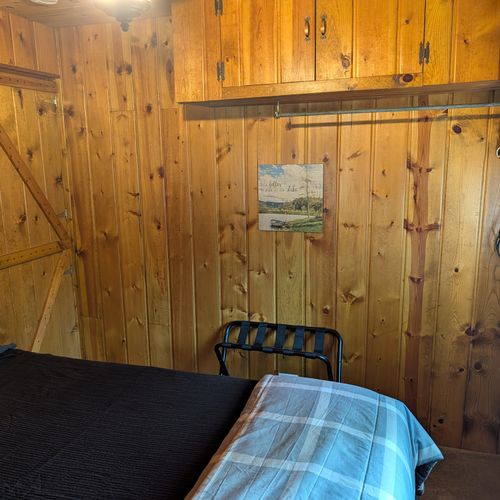 BEDROOM #1:  Features a queen-size bed, nightstand, clothes rack, and luggage stand.