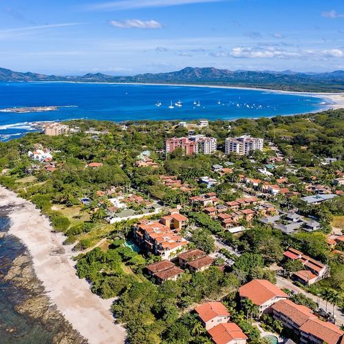 Aerial view of exclusive Playa Langosta neighborhood in Tamarindo area, Costa Rica. Upscale beach community, pristine coastline, tropical canopy, with famous Tamarindo beach visible in the background. Premium location for discerning travelers.