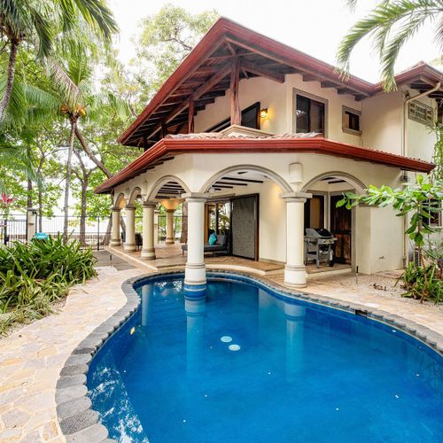 Private kidney-shaped pool and arched colonnade veranda at Casa Blue Lagoon beachfront villa, Tamarindo Beach, Costa Rica.