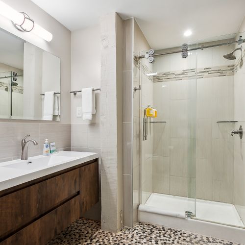 Bathroom w/ glass shower, sink & mirror.