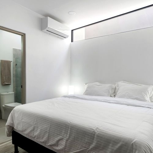 Primary bedroom with queen bed, bedside lighting, air conditioning, and direct en-suite bathroom access in Casa Margarita, Tamarindo, Costa Rica.