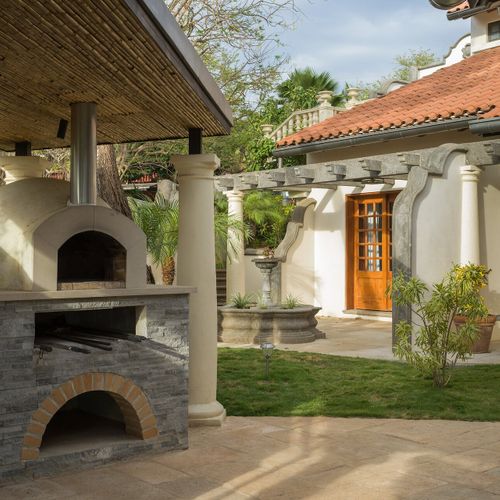 Outdoor kitchen with wood-fired pizza oven, Argentinian asado grill and gas BBQ - built for chef-led dinners under the stars.