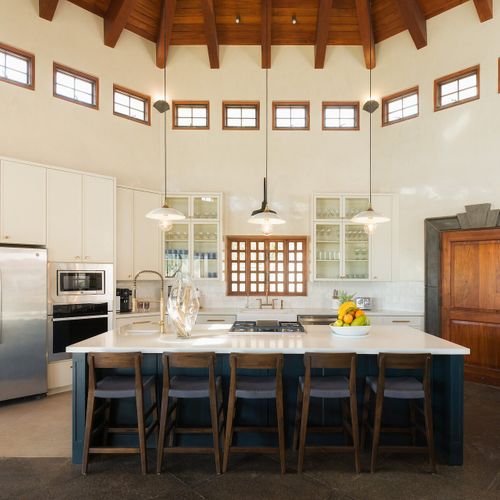 chef island with quartz top, brass fixtures, glass-front cabinetry and gas cooktop.