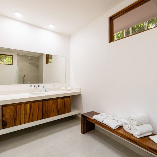 Modern ensuite bathroom with quartz vanity, walk-in rainfall shower and live-edge teak detail at Casa Blue Lagoon, Tamarindo.