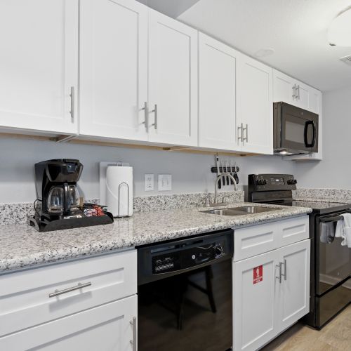Sleek kitchen w/ granite counters, white cabinetry & full appliances.