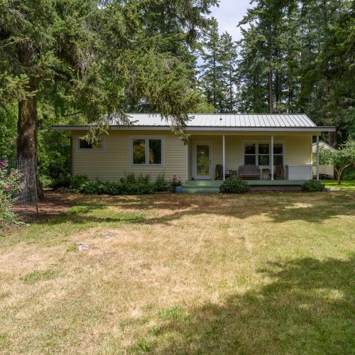 Take in the peaceful setting from the expansive backyard, where a covered porch overlooks a spacious lawn surrounded by mature evergreens. It's the perfect spot to relax, dine outdoors, or enjoy quality time with family and friends.