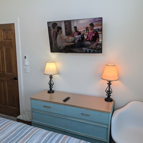 BEDROOM #3 (THIRD FLOOR):  Features a king-size bed, private mini-split A/C unit, ceiling fan, nightstands, reading lamps, chair, television, dresser, closet, private bathroom entrance, and spectacular views of Crystal Lake!