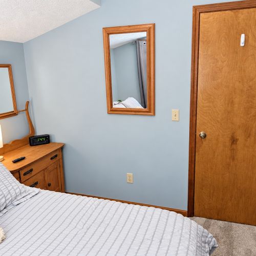 BEDROOM #1 (FIRST FLOOR):  Features a queen-size bed, nightstands, mirror, closet, and a television.