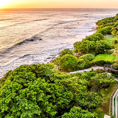 Drone sunset photo over Playa Langosta's coastline and surf break, with the Horizontes Del Mar pool and property visible along the shoreline, Tamarindo.