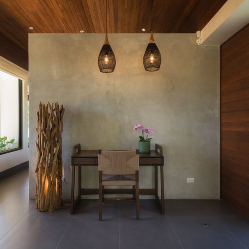 In-suite workspace nook with concrete wall, twin rattan pendant lights and driftwood floor lamp at Casa Oso luxury villa, Tamarindo.
