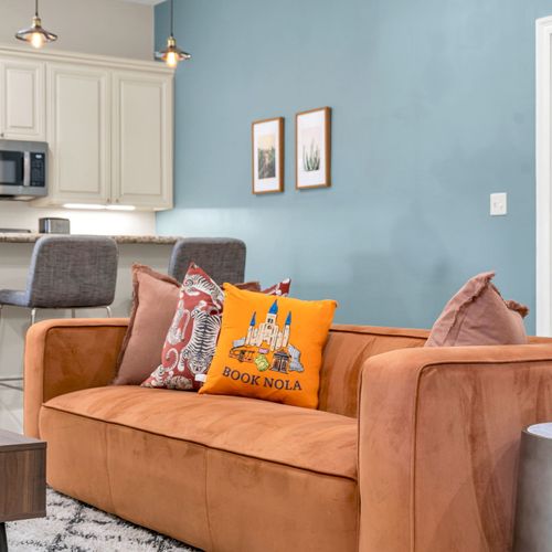 Book NOLA pillows on a cozy orange sofa