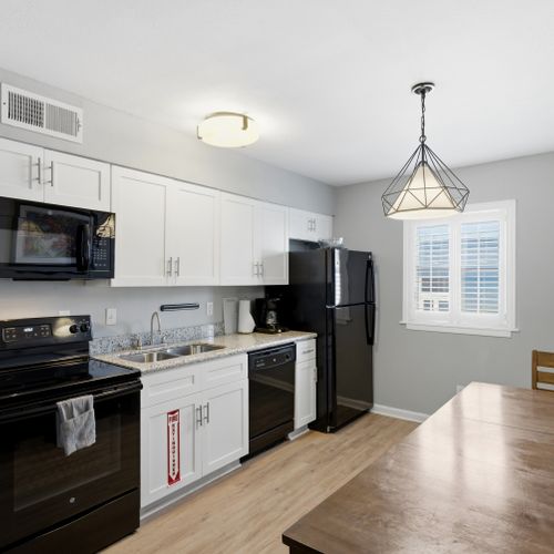 Sleek kitchen w/ black appliances & a dining area ready for home-cooked meals & good company.