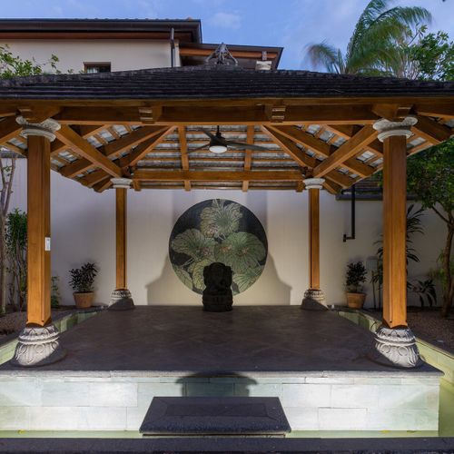 Wood pergola yoga and meditation pavilion with raised platform and stone column accents at Casa Libelula luxury estate, Tamarindo.