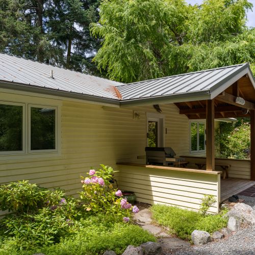 Enjoy the covered front porch with comfortable seating and a propane grill, all set within beautifully landscaped grounds and a quiet natural setting.