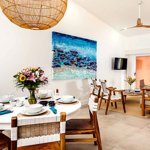 Open-concept dining and living area with seating for six, a rattan pendant light