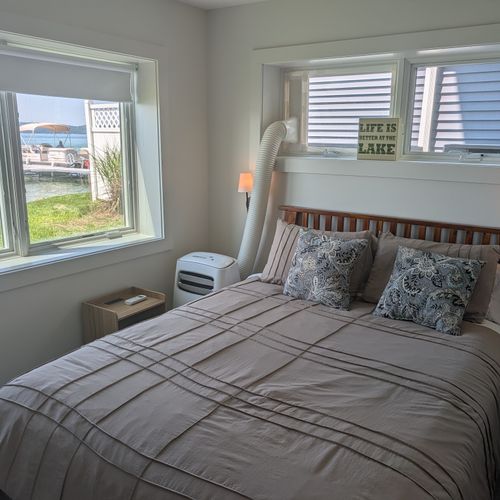 BEDROOM #4 (FIRST FLOOR):  Features a queen-size bed, private A/C unit, ceiling fan, television, dresser, mirror, nightstand, reading lamps, a clothes rack, and great views of Crystal Lake!