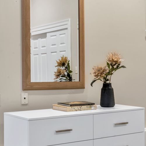 Warm wood mirror over a bright white dresser