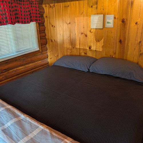 BEDROOM #1:  Features a queen-size bed, nightstand, clothes rack, and luggage stand.