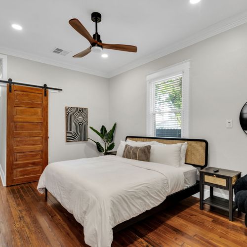 Drift off in this airy bedroom w/ a rustic sliding barn door, ceiling fan & soft natural light