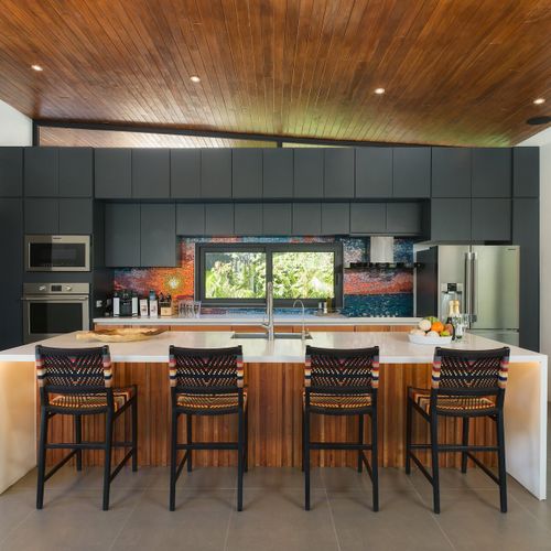 Gourmet chef's kitchen with quartz island, woven counter stools and Costa Rican mosaic backsplash at Casa Oso luxury villa, Tamarindo.