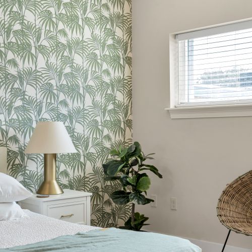 Bedside lamp beneath a breezy palm print