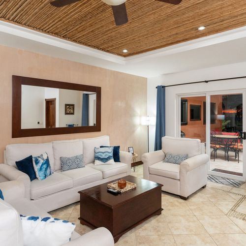 Open concept living room with comfortable sofa and direct balcony access at luxury Playa Langosta condo, Tamarindo, Costa Rica. Flowing indoor-outdoor space, natural light, ocean breeze, and tropical garden views. Steps from beach.