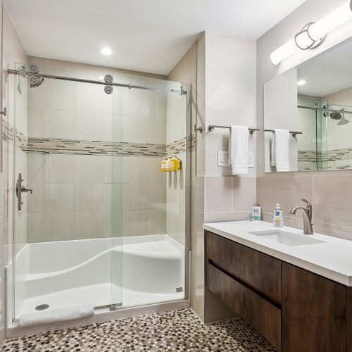 Bathroom w/ glass shower & tub combo, sink & vanity.